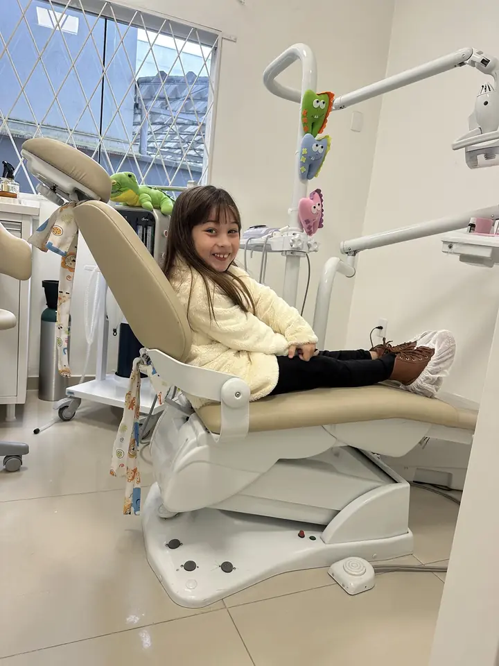 Menina sorrindo na cadeira do consultório